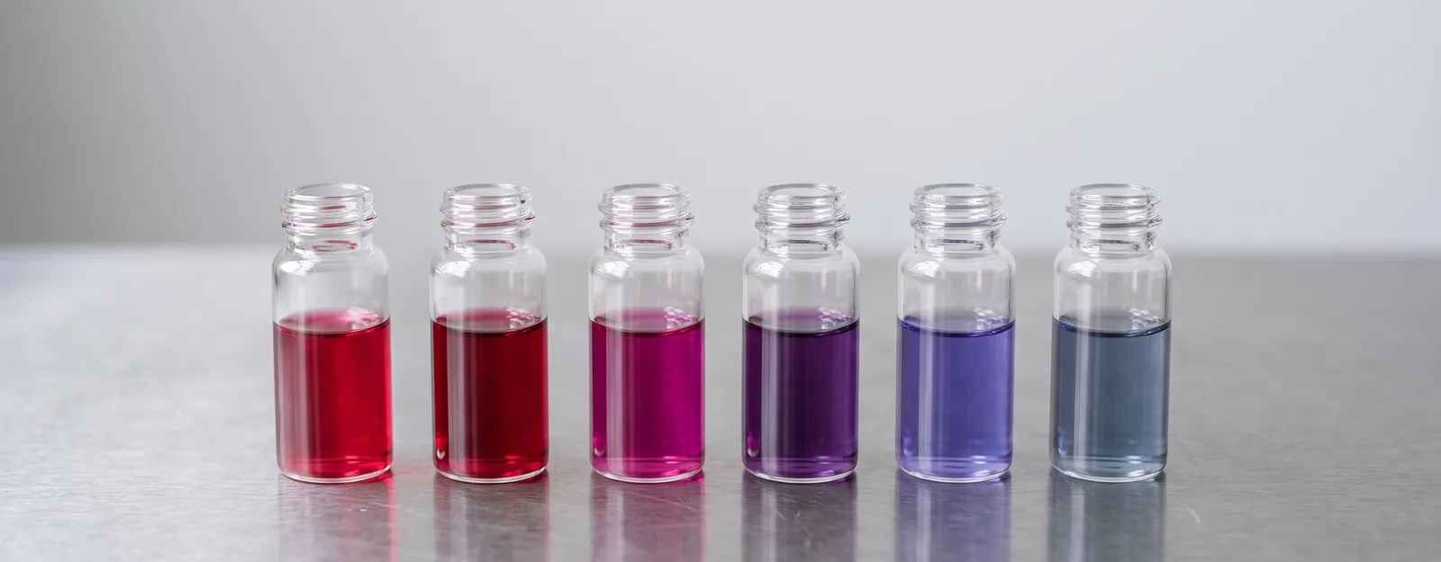 Six vials of gold nanoparticle solutions, from ruby red through purple to blue-grey
